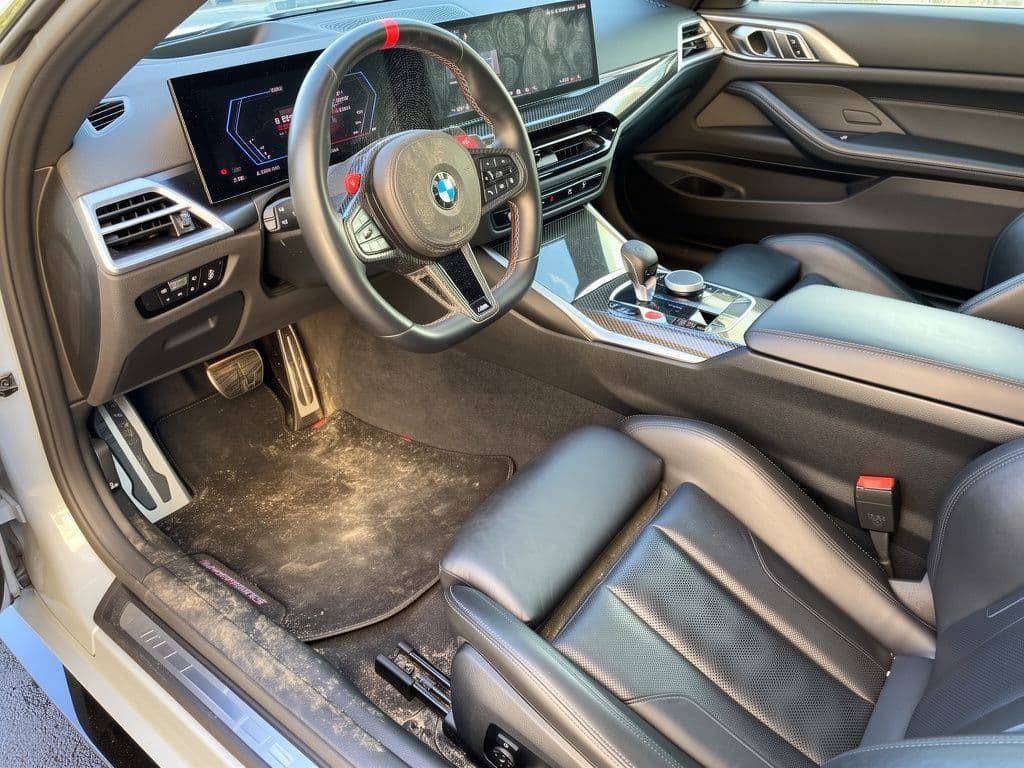 The same BMW M interior before detailing, with soiled carpet and mats
